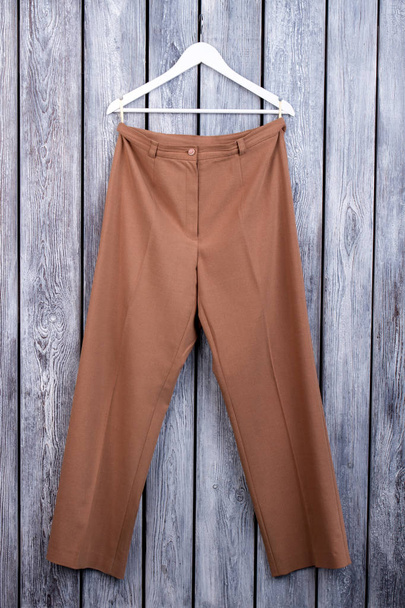 Flat lay brown woman trousers on hanger. - Fotó, kép