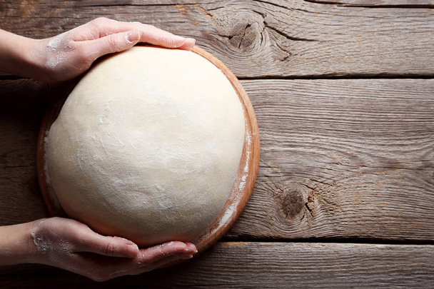 Female hands holding raw dough - Foto, afbeelding