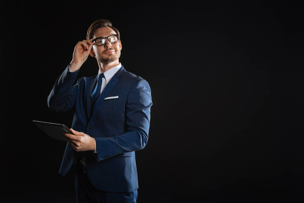 Successful bespectacled man holding the tablet touching to his glasses. - Fotoğraf, Görsel