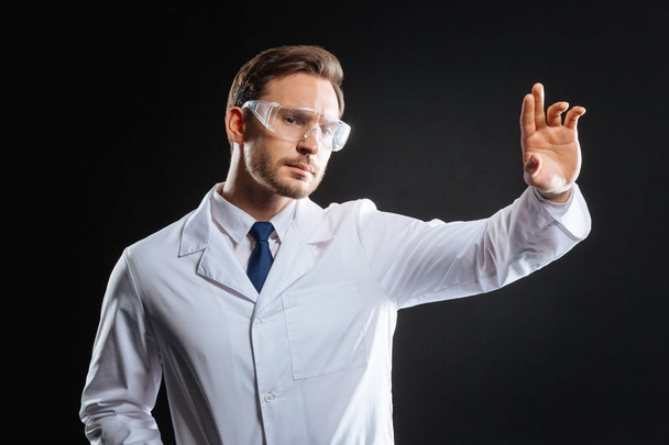 Thoughtful bespectacled scientist holding hand up and looking aside. - Foto, immagini