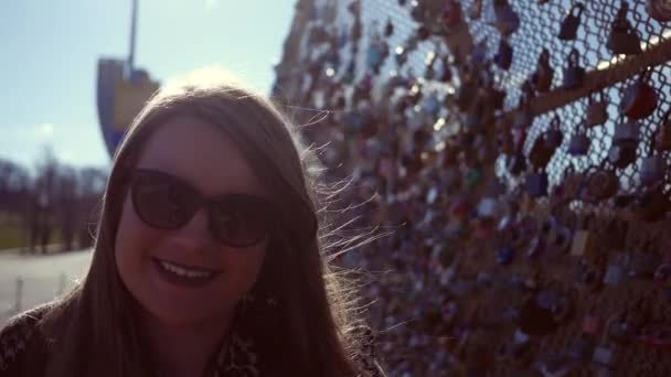 Ładny modny brunetka Blondynka uśmiecha się do kamery na miejski most, w pobliżu centrum miasta - Materiał filmowy, wideo