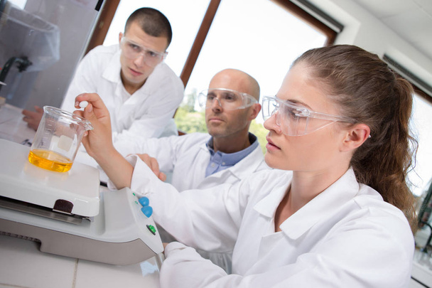 mannelijke medische onderzoekers uit te voeren tests met gele vloeistof - Foto, afbeelding