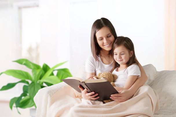 sweet little girl with mother reading book - Фото, изображение