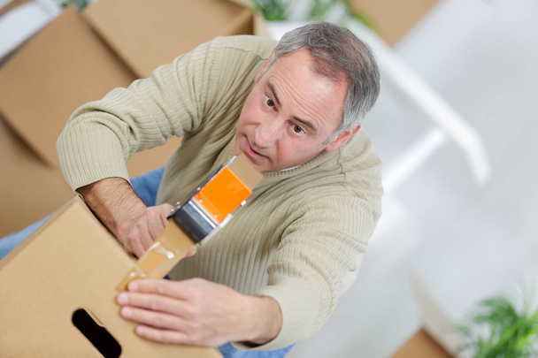 man packing a moving box using an adhesive tape - Foto, Imagen