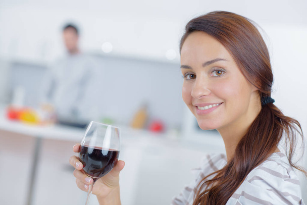 Lady holding glass of wine, partner in background - Zdjęcie, obraz