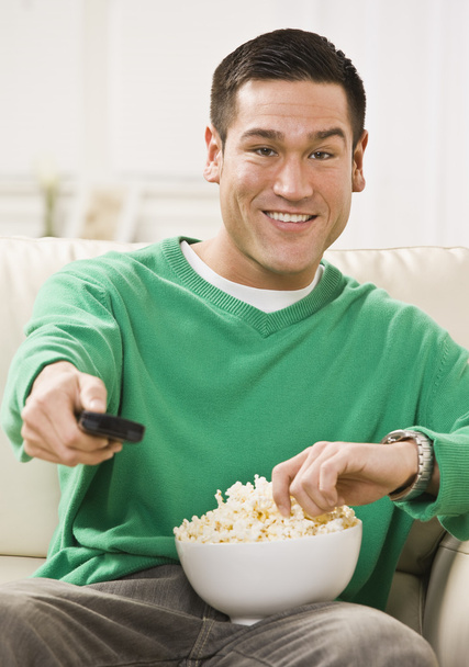Attraente uomo asiatico con popcorn e telecomando
 - Foto, immagini
