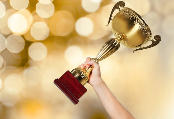 Hand holding golden Trophy on blurred background  - Zdjęcie, obraz