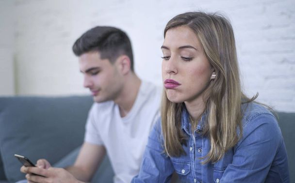 young attractive couple in relationship problem with internet mobile phone gambling addict boyfriend ignoring sad neglected and bored girlfriend  - Φωτογραφία, εικόνα