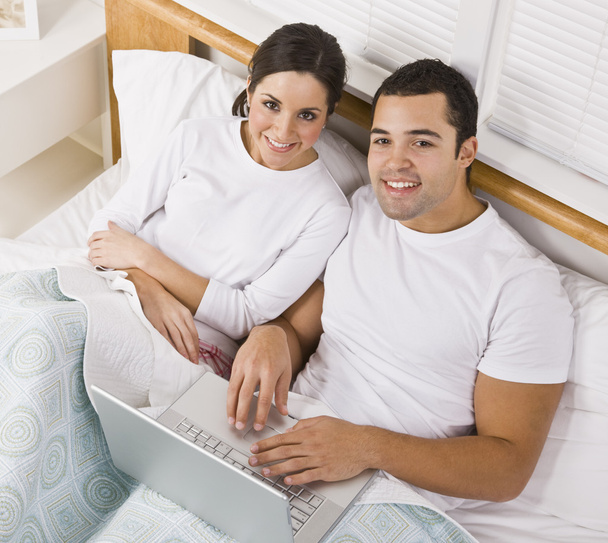 Ζευγάρι στο κρεβάτι με φορητό υπολογιστή - Φωτογραφία, εικόνα