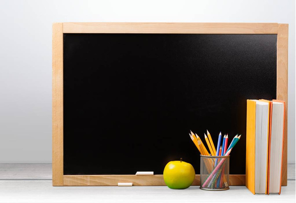 μήλο σε βιβλία με μολύβια και άδειο μαυροπίνακα - επιστροφή στο σχολείο - Φωτογραφία, εικόνα