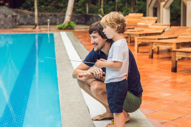 Father and son playing with a remote controlled boat in the pool. - Foto, Imagem