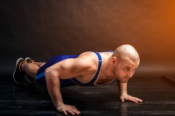 Genç atletik biri zor ve mavi şort güreş mavi siyah saçlı bir izole arka planda bir fotoğraf Studio şınav mı - Fotoğraf, Görsel