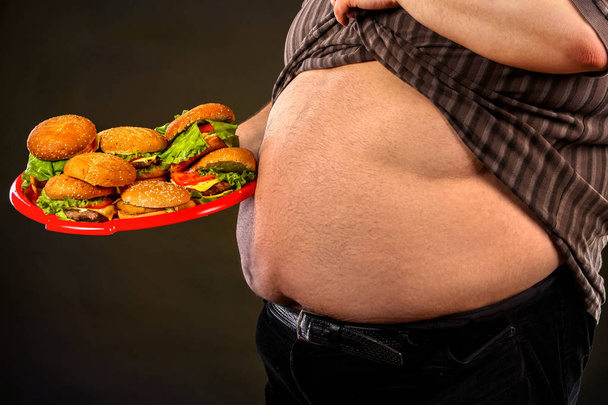 Muž břišní tuk s rychlým občerstvením pro osoby s nadváhou hamberger. - Fotografie, Obrázek