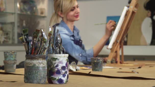 Enfoque selectivo en un montón de pinceles artista femenina que trabaja en su pintura
 - Imágenes, Vídeo