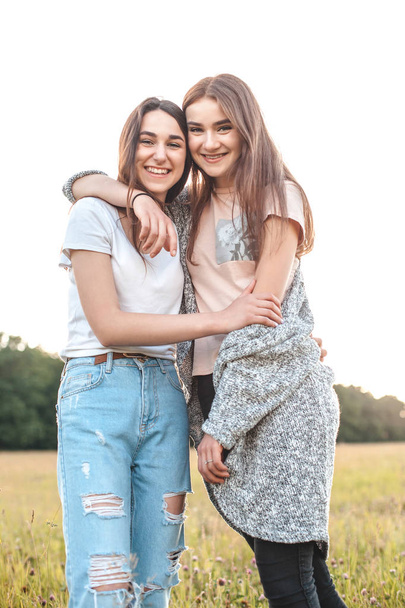 Two girls hugging on green field in daytime - Foto, immagini