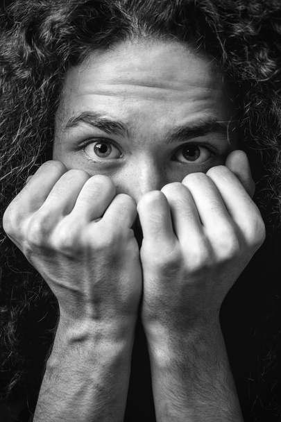 Monochrome portrait of man covered his face with his fists - 写真・画像