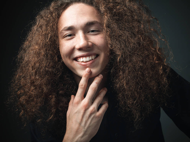 Portrait of smiling young man with curly hair in studio - Photo, Image