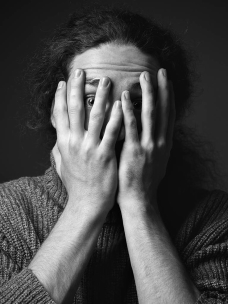 Monochrome portrait of young man with curly hair in desperateness - 写真・画像