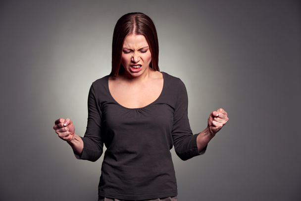θυμωμένος νεαρή γυναίκα πάνω από σκούρο φόντο - Φωτογραφία, εικόνα