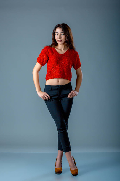 Young woman in blank red t-shirt standing against grey background - 写真・画像