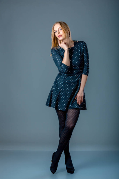 Beautiful caucasian plus size woman in dark blue polka-dot dress. Full length portrait of attractive young female posing over grey background. - 写真・画像