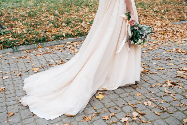 Beautiful bride with a wedding bouquet in their hands outdoors in a park - Photo, Image