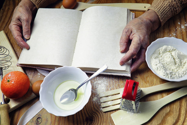 Książkę kucharską otwarte w rękach starszą kobietę - Zdjęcie, obraz