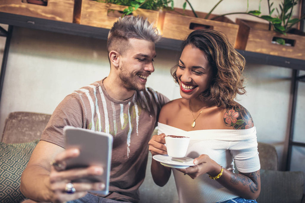 Szczęśliwa para przy użyciu cyfrowych tabletów siedząc w kawiarni, zrobić zdjęcie selfie - Zdjęcie, obraz