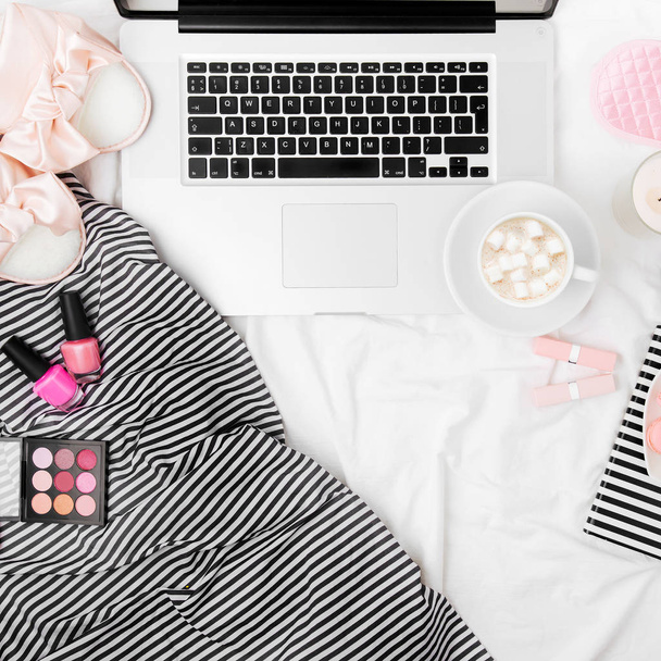 Fashion blogger workspace with laptop and woman accessory in bed. Flat lay, top view - Foto, Bild