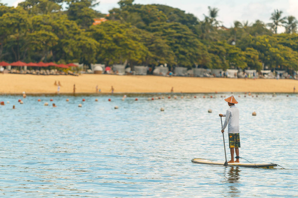 Genç adam bir Sup tahta üzerinde yüzer. Bir sörf üzerinde mavi su ile deniz macera. - Fotoğraf, Görsel