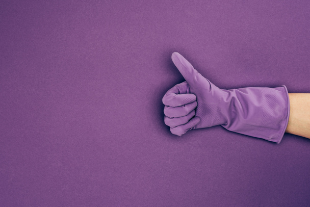 przycięty obraz kobiety pokazano kciuk w gumowe rękawice ochronne na białym tle na fioletowo - Zdjęcie, obraz