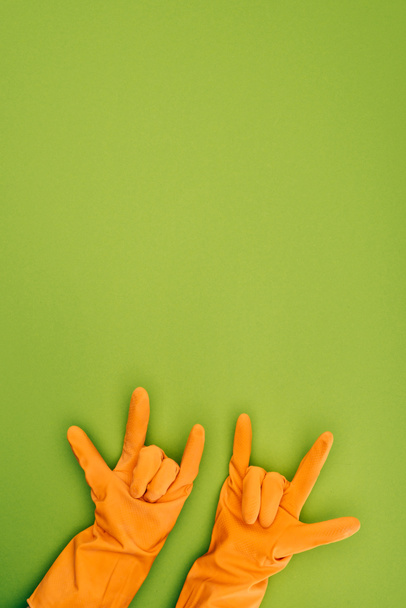 обрезанное изображение женщины, показывающей скальные знаки в резиновых защитных перчатках, изолированных на зеленом
 - Фото, изображение
