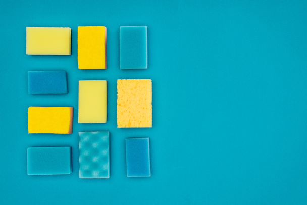 vista superior de esponjas de lavado amarillas y azules aisladas en azul
 - Foto, imagen