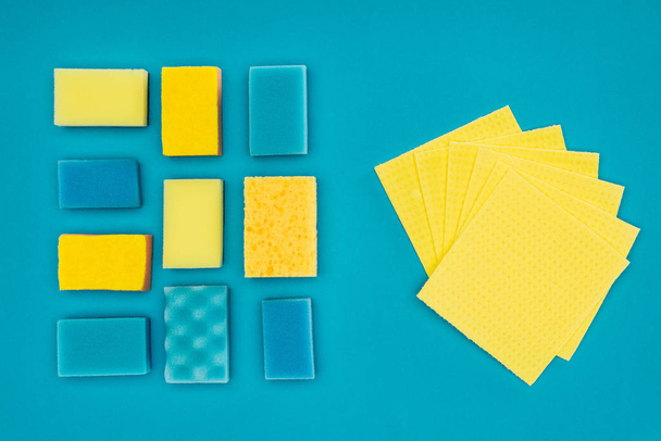 vista superior de esponjas y trapos de lavado amarillos y azules aislados en azul
 - Foto, Imagen