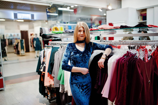 Blonde girl in blue dress in the clothing store boutique. - Foto, afbeelding
