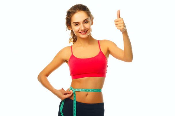 Woman measuring her waist and showing hand ok sign over white ba - Фото, зображення