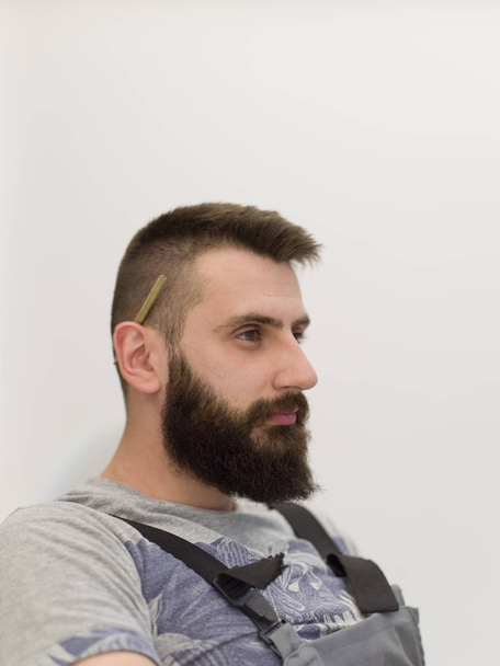 portrait of bearded hipster handyman with pen behind ear isolated on white background - Foto, afbeelding