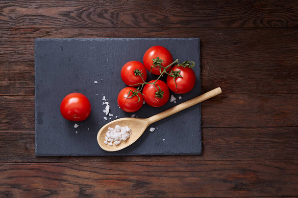 Vegetarian still life with fresh grape tomatoes, pepper and salt in wooden spoon on wooden background, selective focus - Valokuva, kuva