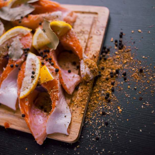Sliced salmon steaks with lemon and spices. On a wooden Board. - Fotografie, Obrázek