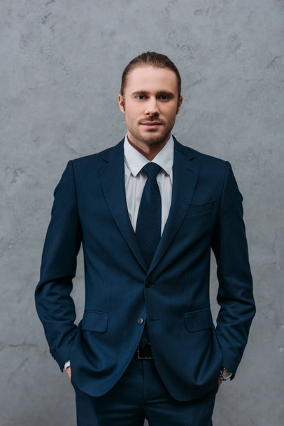 young handsome businessman in stylish suit in front of concrete wall - Photo, image