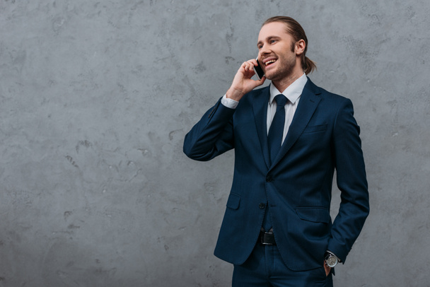 young happy businessman talking by phone in front of concrete wall - Photo, Image