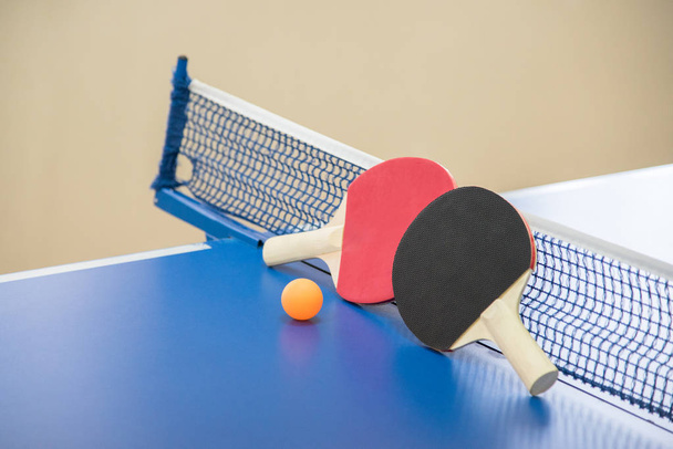 Bola naranja para tenis de mesa y dos raquetas de rojo y negro co
 - Foto, Imagen