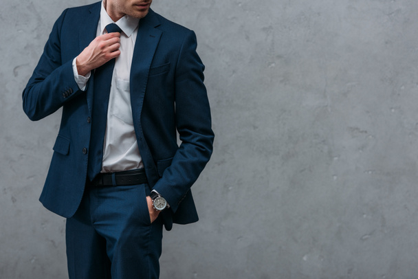 Schnappschuss eines gutaussehenden Geschäftsmannes im schicken Anzug vor Betonwand - Foto, Bild
