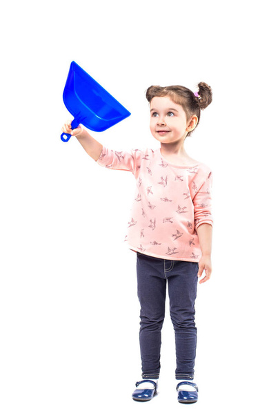 Little girl with a blue dustpan for cleaning on a white background, isolated on white - Foto, afbeelding