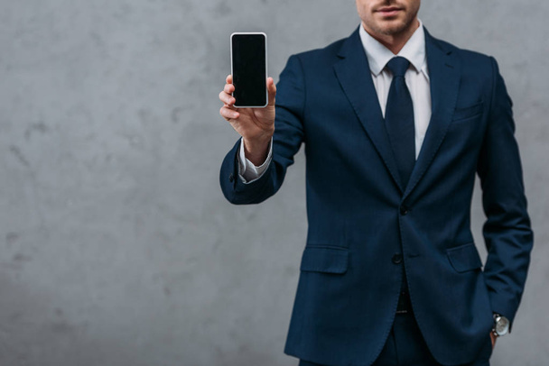 cropped shot of businessman showing smartphone at camera - Foto, afbeelding