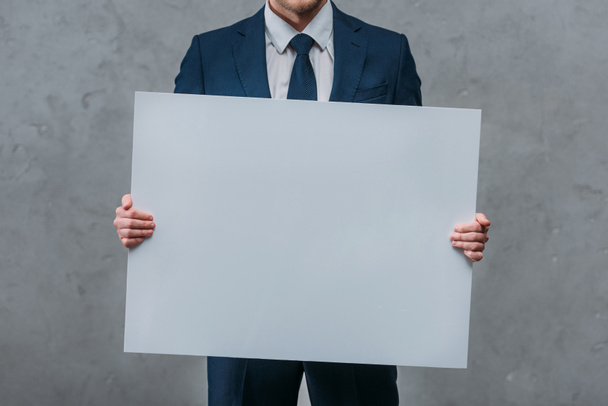 cropped shot of businessman holding blank board in front of concrete wall - Photo, Image