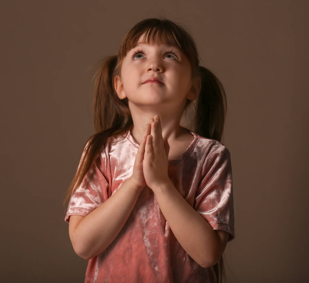 Religious Christian girl praying on dark background - Фото, изображение