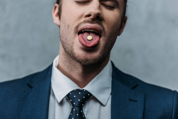 retrato de cerca del hombre de negocios adicto que sobresale de la lengua con la píldora mdma
 - Foto, Imagen