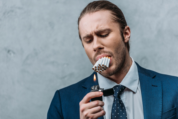 recortado disparo de hombre de negocios con la boca llena de cigarrillos tratando de fumar - Foto, Imagen