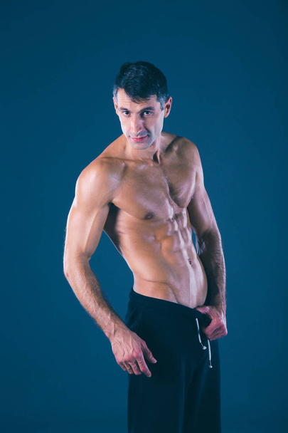 muscular man. Muscular man on a grey background showing muscles. Fitness instructor. Fitness professional. Workout. Mens fitness. - Foto, immagini